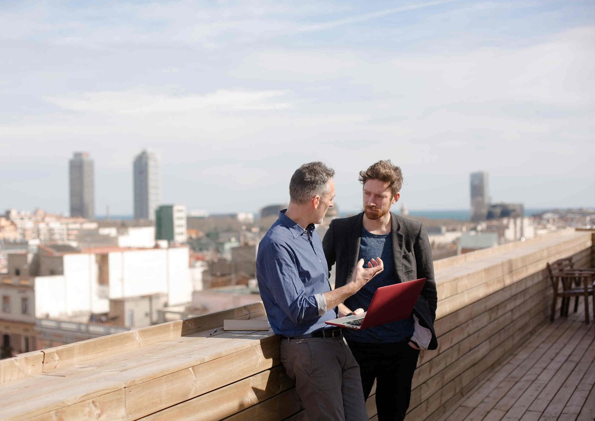 Photo of two co-workers having a discussion on the rooftop