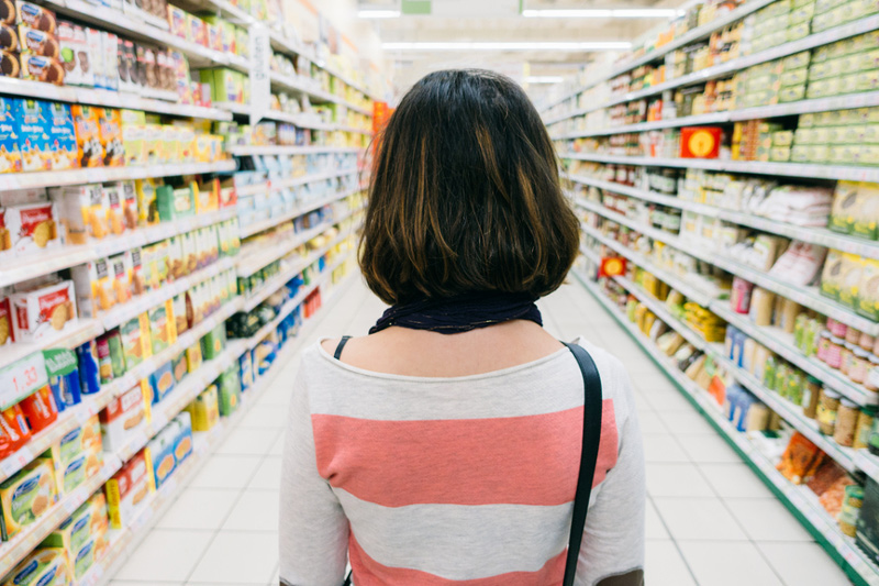 Photo of the back of a women looking down a grocery store aisle