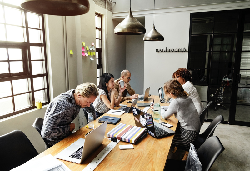 Photo of a team collaborating around a long, wooden desk.