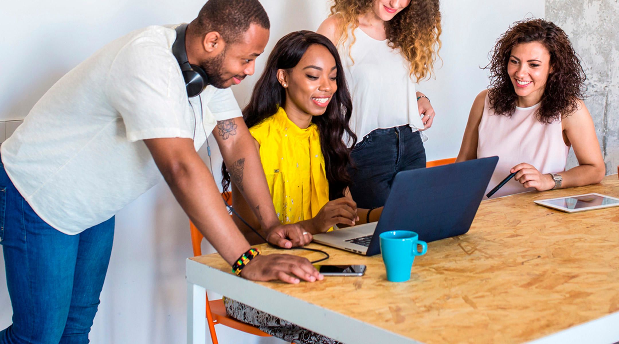 Photo of a team happily collaborating around a laptop