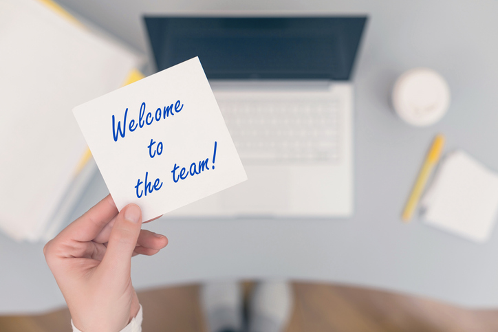 Hand holding a "Welcome to the team!" sticky note