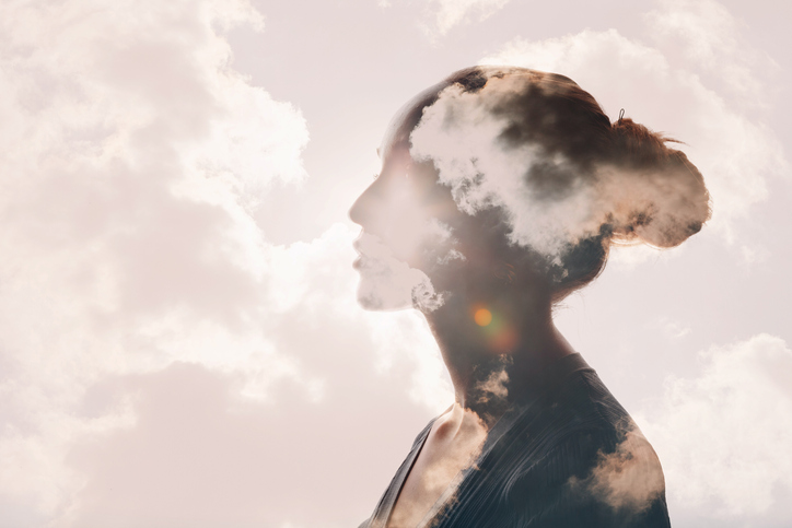 Multiple exposure clouds and sun on female head silhouette