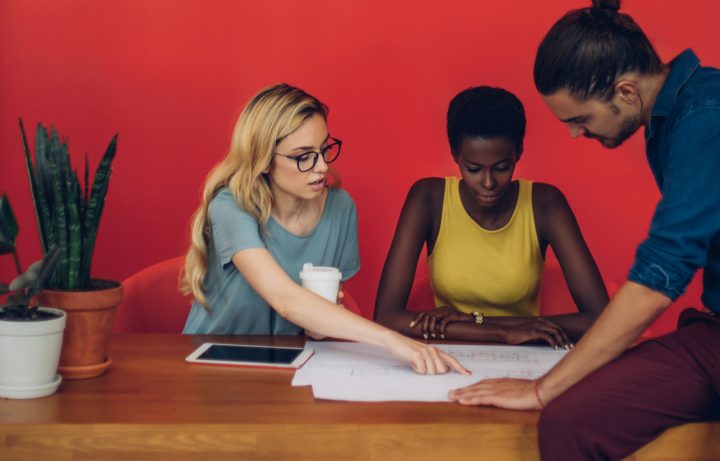 Photo of co-workers collaborating around some paper drawings